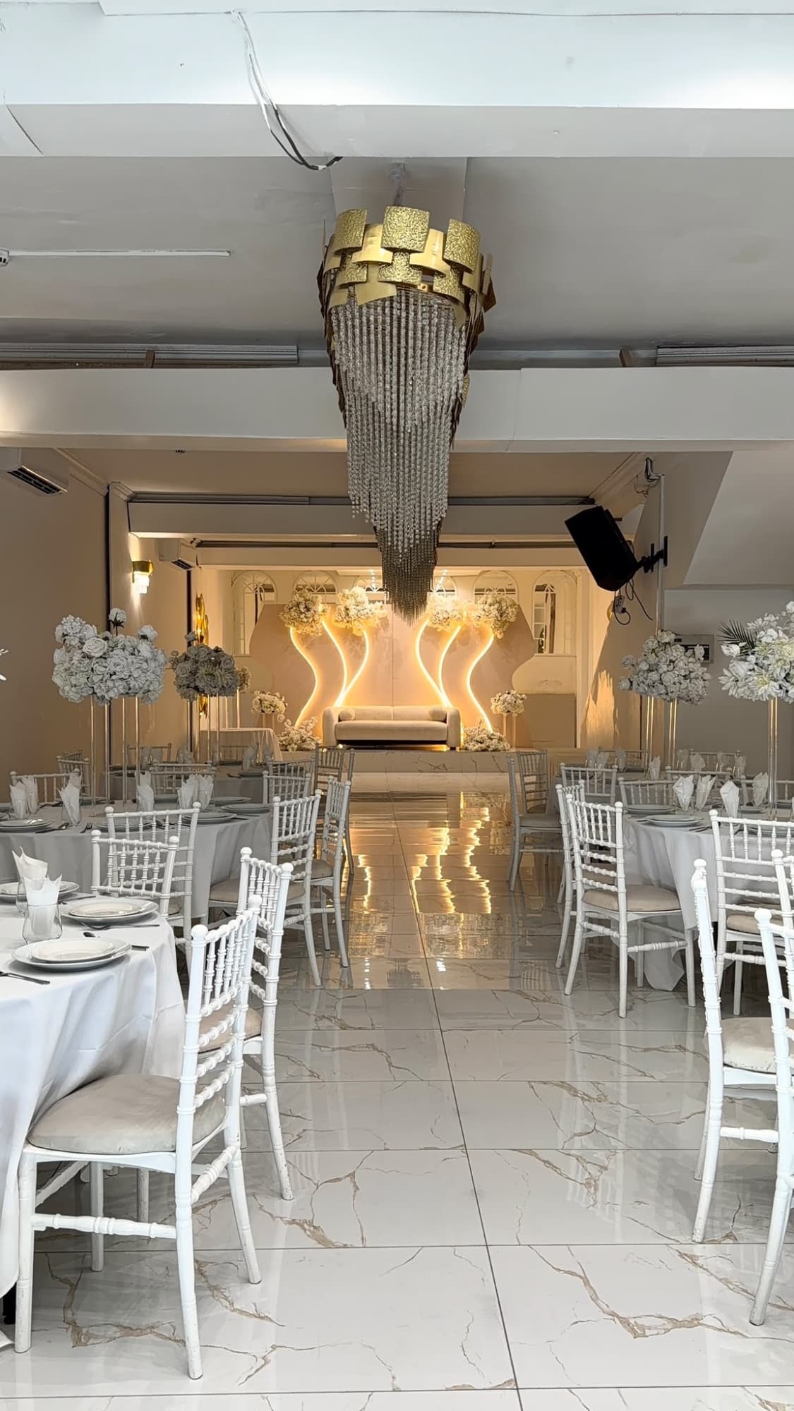 White chairs and marble flooring leading to the stage and its gold light