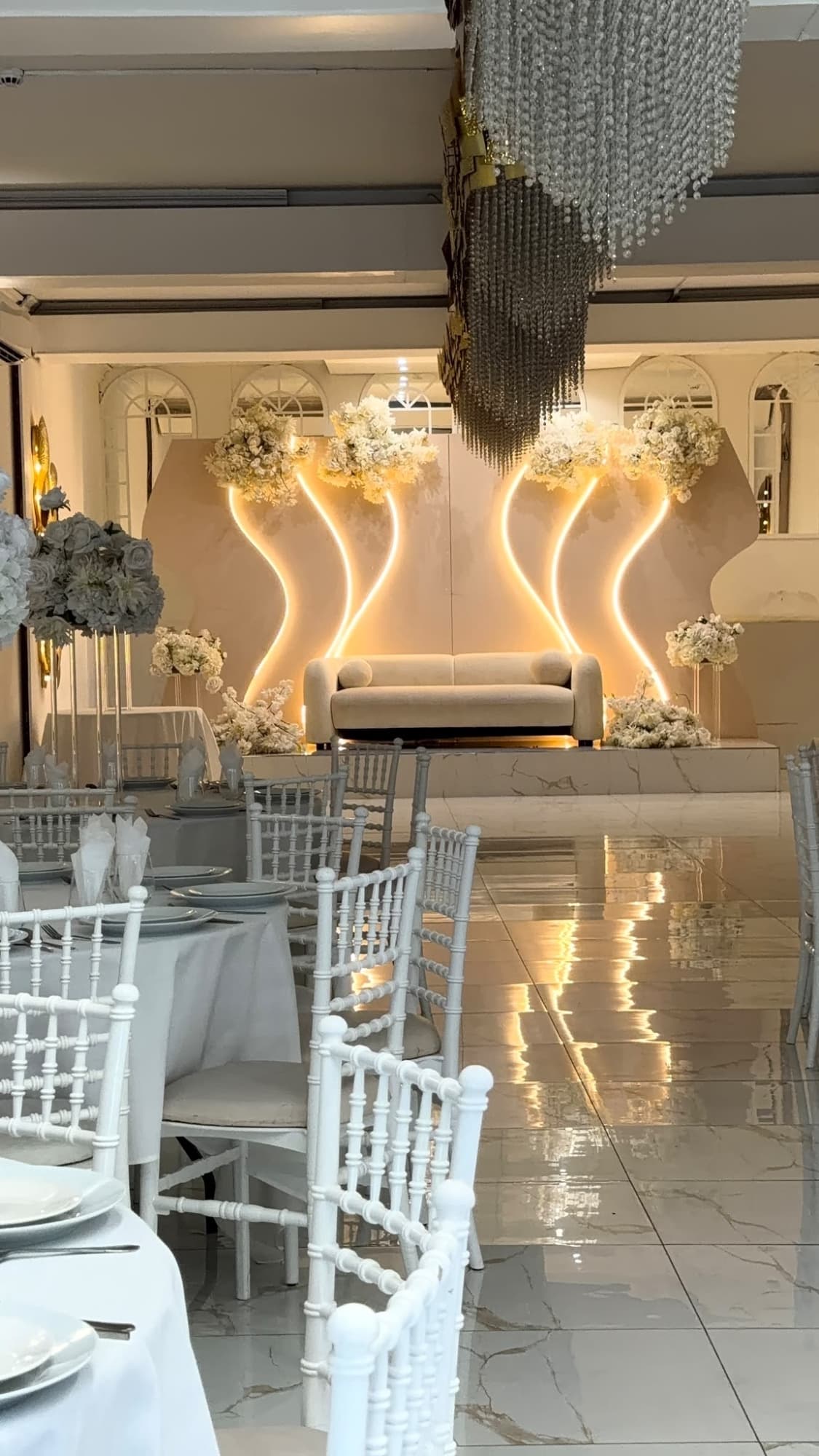 Laid tables facing the stage, with the chandelier above the aisle