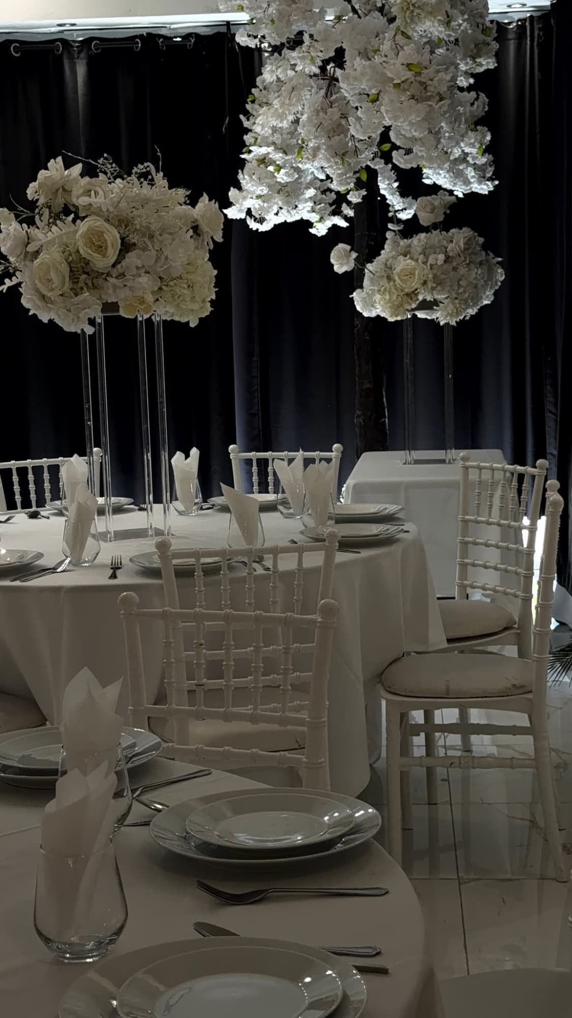 Tall white flowers above tables dressed in white linen