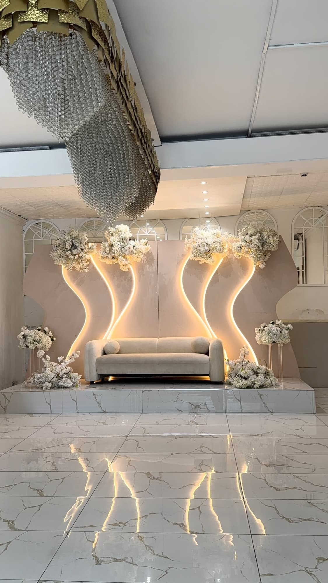 The stage sofa against curved gold lighting and clouds of white flowers